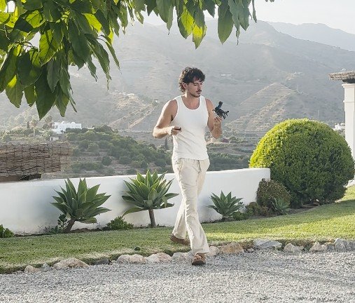 Piloto de Nilu Films preparando un dron en un jardín con vistas a las montañas